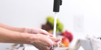 persona lavándose las manos con fruta de fondo
