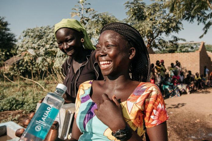 mujer africana riendo con una botella de agua en la mano