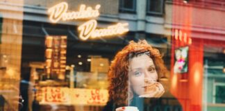 mujer tomando café en una cafetería y mirando por la ventana