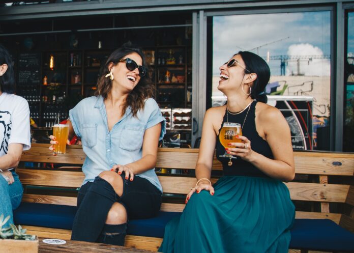 dos chicas bebiendo cerveza en una terraza