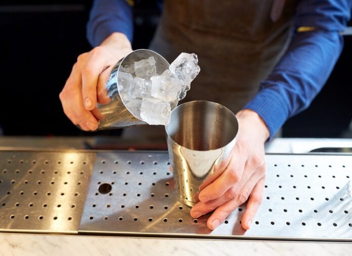 Bartender With Ice And Shaker At Cocktail Bar