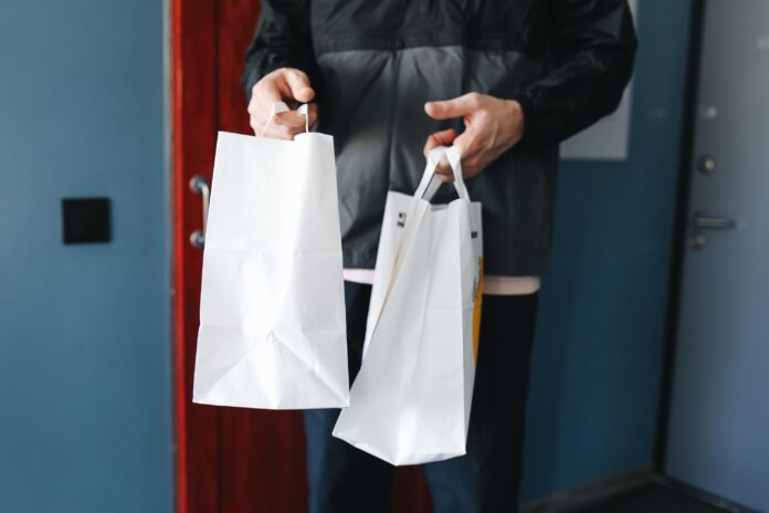 hombre entregando dos bolsas de papel blancas