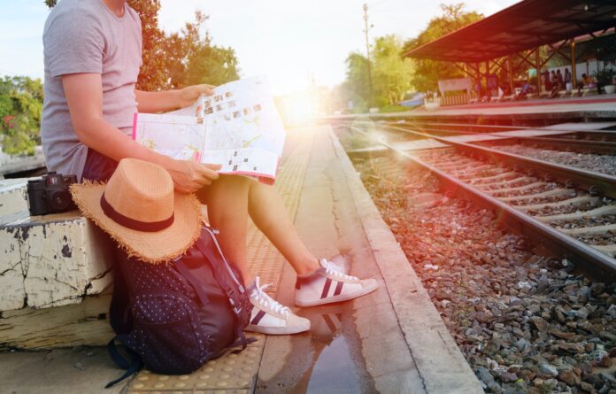 mujer con mapa y mochila esperando al tren